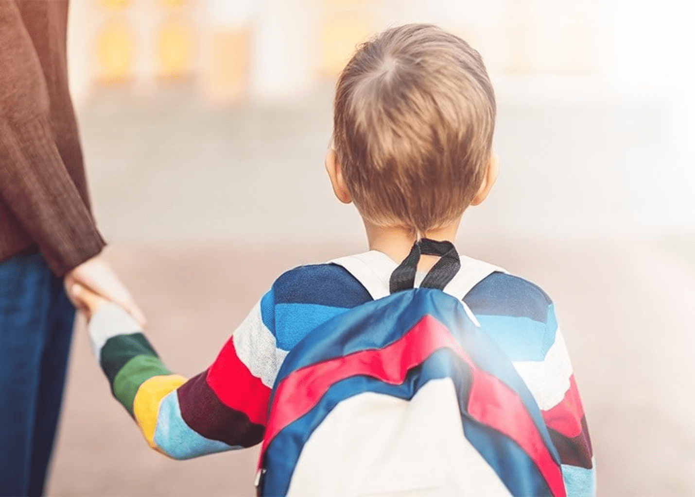 Very young boy, wearing a backpack, holds his mother hand