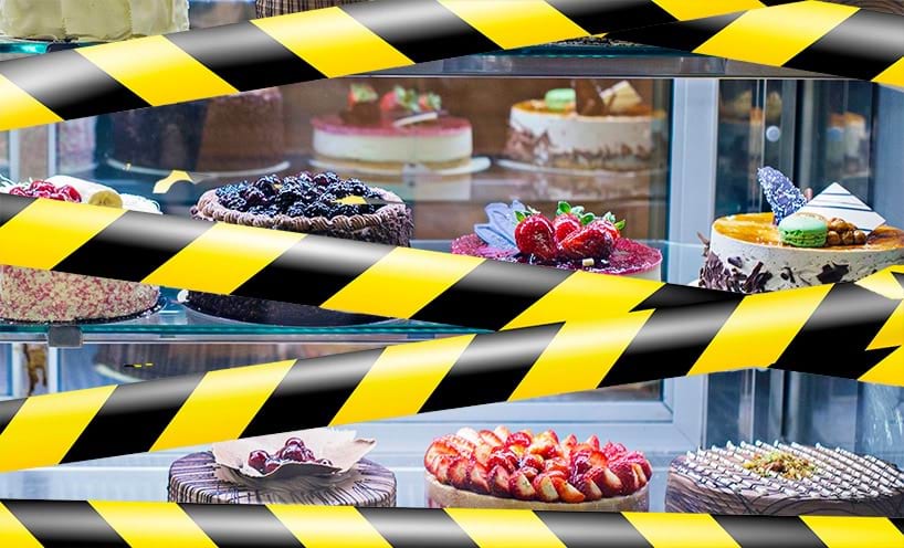 A cake shop front window covered in warning tape