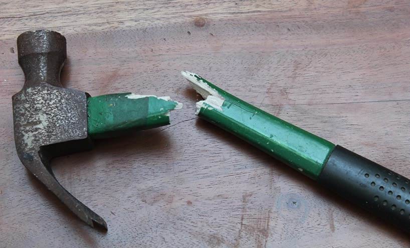 Broken hammer. Hammer with a broken handle on a wooden background.