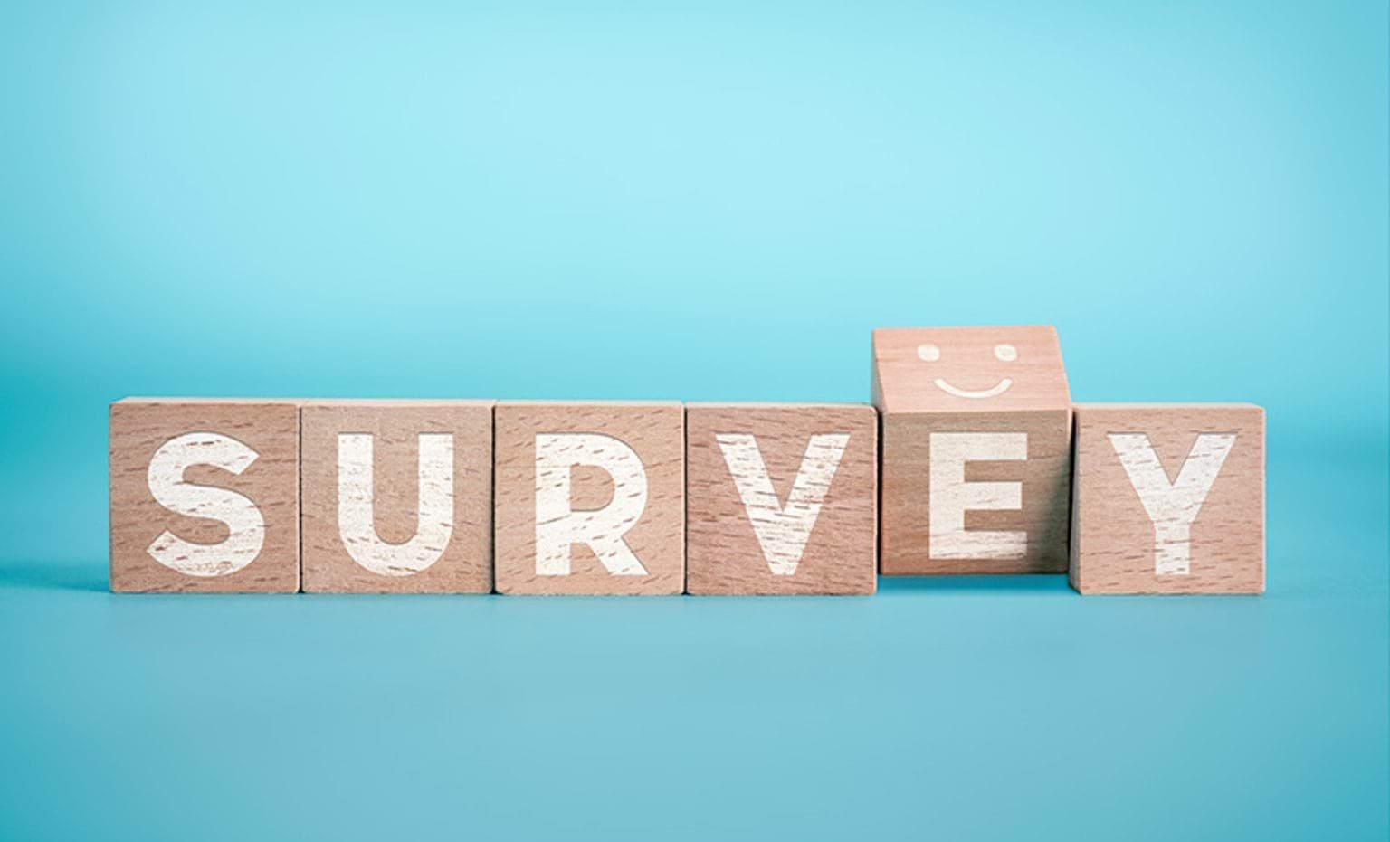 The word "survey" spelled out on wooden cubes, with the letter "e" slightly turned to show a smiley face on top of the cube.