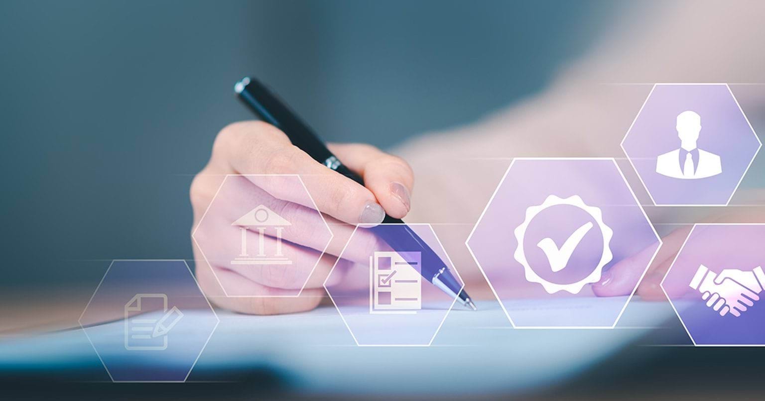 Image of a hand holding a pen while reviewing an agreement and preparing to sign it.