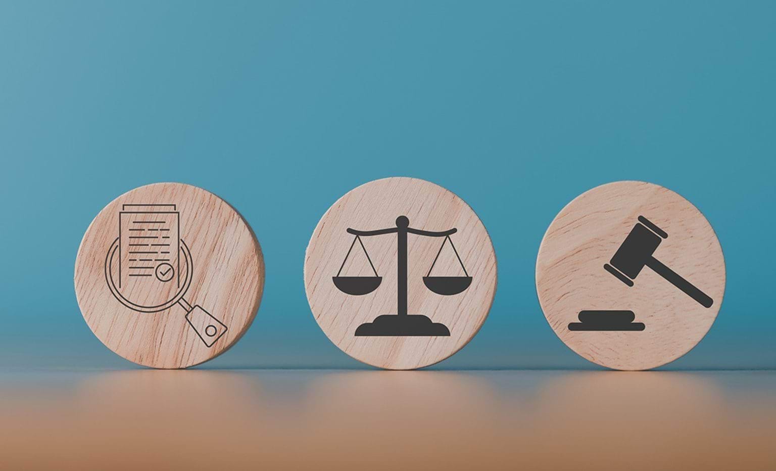 Wooden blocks sit on a table each with a symbol representing, investigation, justice and legal decision.