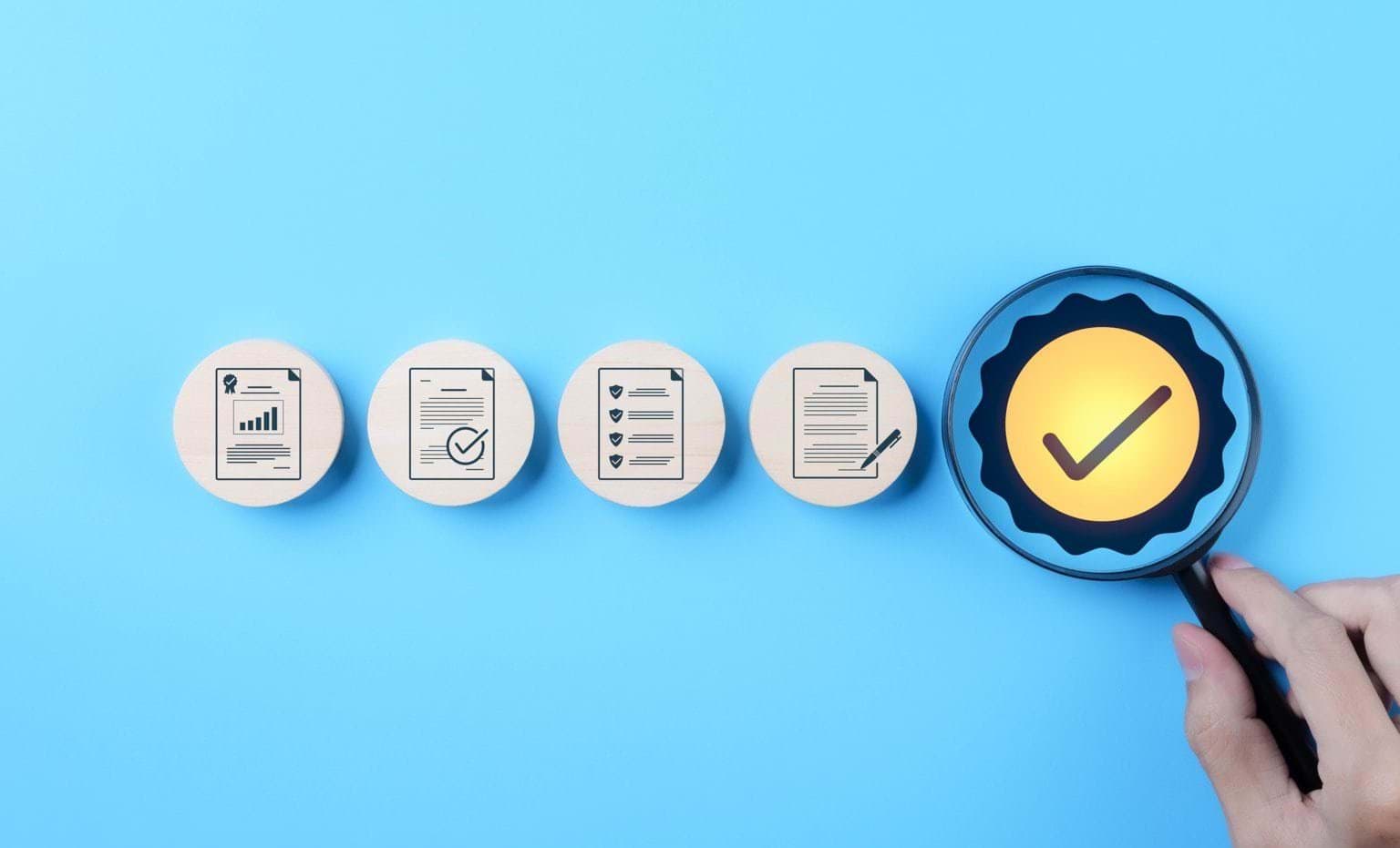 Hand holding magnifying glass over checkmark symbol, alongside icons representing quality control, certification, and assurance on blue background