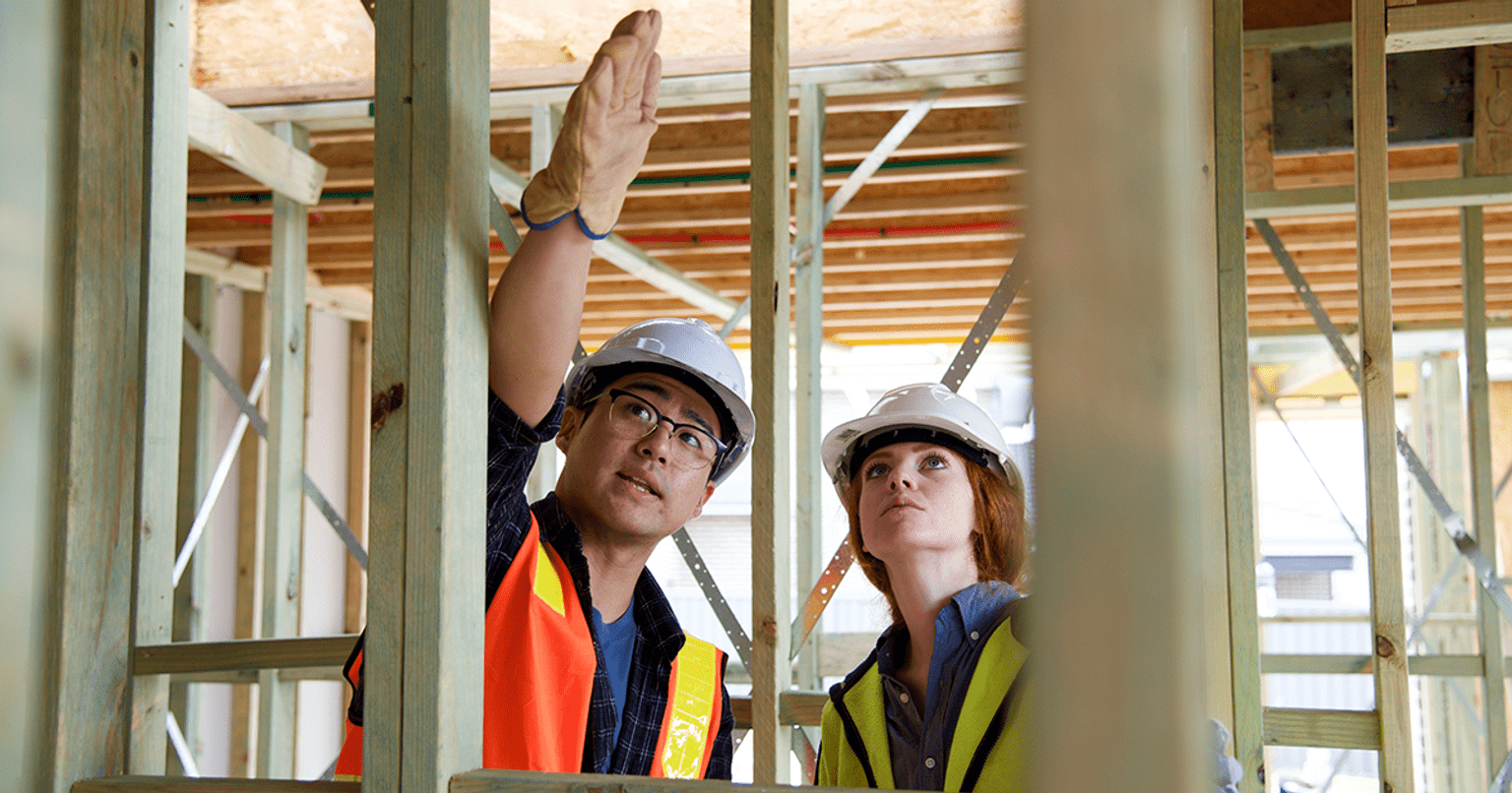 Two construction workers, a man and a woman, are engaged in a work-related conversation